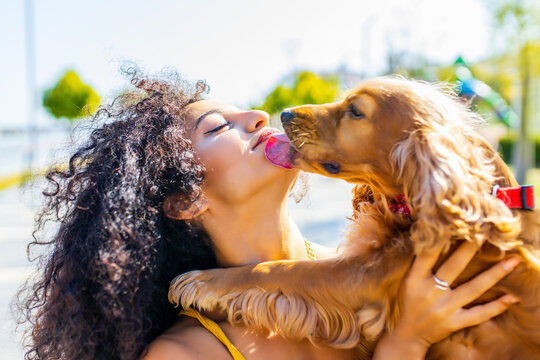 beautiful young woman with long dark curly hair with american cocker dog outdoors