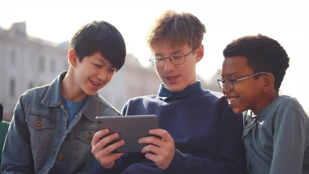 Happy multiethnic smiling teenage friends use smartphone outdoors. Realtime