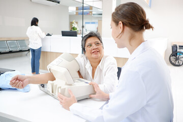 Obraz premium Female doctor measuring blood pressure, old woman patient, medical concept.