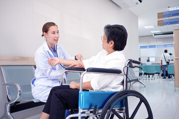 Obraz premium Female doctor using a stethoscope examining an elderly female patient sitting on a wheelchair inside a hospital medical concept.