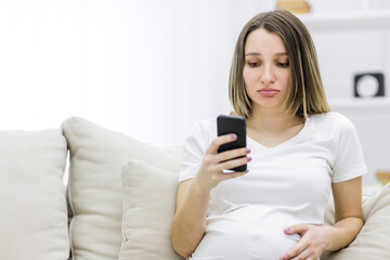 Photo of pregnant woman with the phone looking sad.