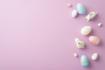 Easter concept. Top view photo of colorful pink white blue eggs and ceramic easter bunnies on isolated pastel violet background with copyspace