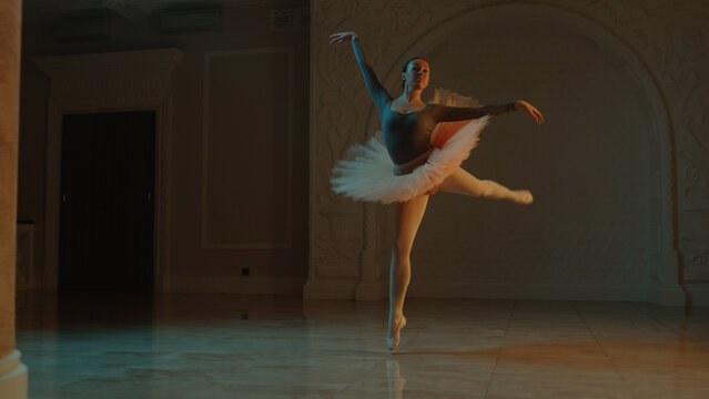 Cinematic shot of graceful female ballet dancer on choreography rehearsal in theater lobby, practicing elegant movements. Ballerina in tutu before performance in opera. Classical theatrical ballet art