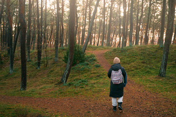 Fototapeta premium Photo from the back of woman discovering forest. Concept of traveling and outdoors wandering.