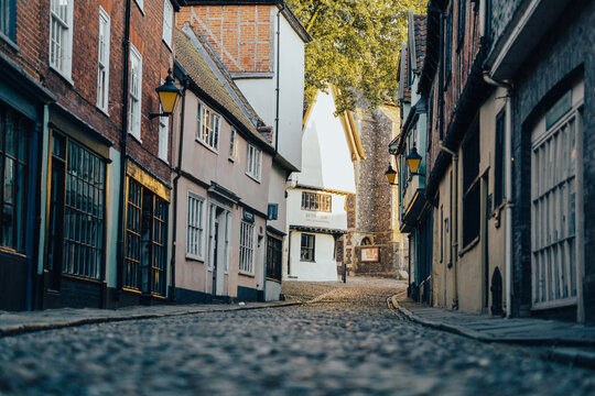 Low down photo of an old English cobbled road and a row of shops, traditional historic buildings, beautiful town