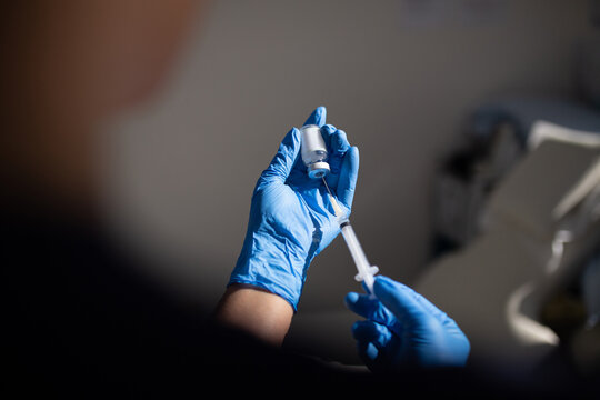 Close up shot of a syringe being inserted to a medicine glass vial by a healthcare worker