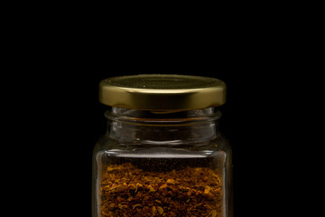 Top part and lid of glass jar filled with chili powder. Isolated on black.
