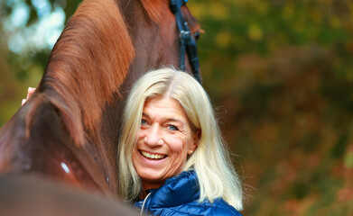 Woman laughing in portrait with her horse Focus on woman's head, horse in out of focus in...