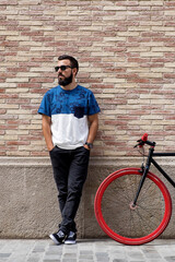 Fototapeta na wymiar Cool guy with bicycle near brick wall