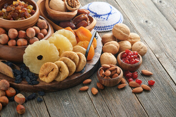 Tu Bishvat celebration concept. Mix of dry fruits and nuts almonds, hazelnuts, walnuts, apricots, prunes, cherries, raisins, dates, apples, figs over wooden table. Jewish holiday, new year of trees.