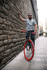 Cool male with bike at wall