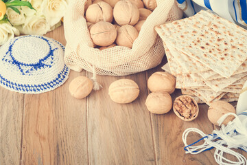 Passover celebration concept. Matzah, red kosher and walnut. Traditional ritual Jewish bread matzah, kippah and tallit on old wooden background. Passover food. Pesach Jewish holiday. Toned image.