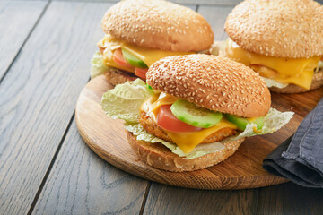 Homemade fish burger with vegetables on rustic wooden board. Side view, close up. Menu.