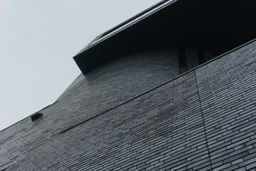 nowoczesny budynek z ciemnej cegły na tle jasnego nieba