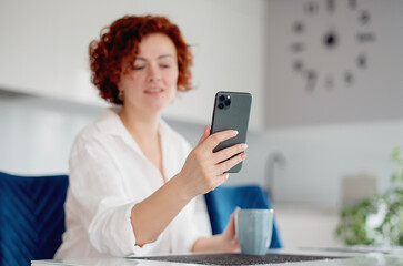 Portrait of a smiling casual woman holding smartphone at home