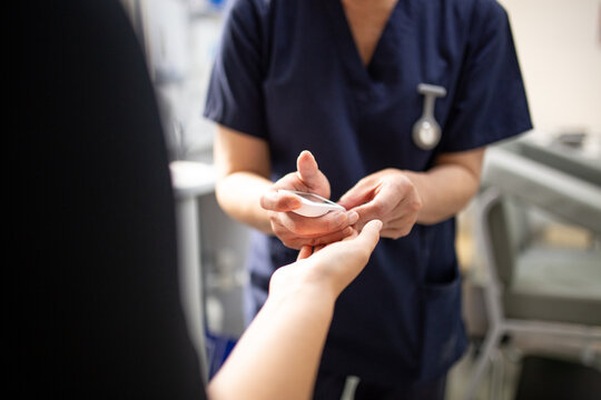 Health worker getting a blood sample from a woman using a blood lancet in the clinic