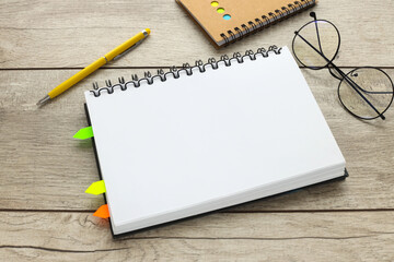 Top view of wooden table with open notebook, glasses, stickers