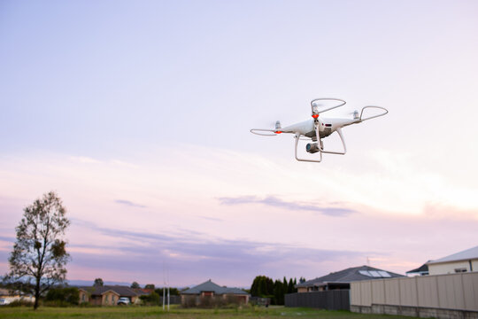 RPA drone flying over edge of suburban area at dusk