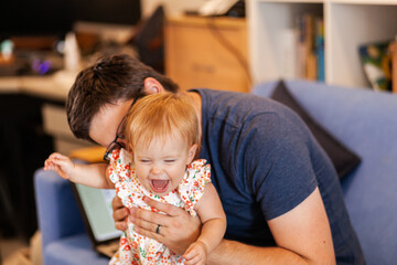 Baby girl laughing as daddy plays and tickles her