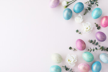 Holiday Easter composition of colorful Easter eggs with golden decorations on white table top view. Flat lay.