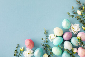 Easter greeting card with pastel easter eggs decorated flowers and green eucalyptus on blue table...