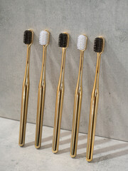 Toothbrushes with black and white bristles stand in a row, leaning against a marble wall.