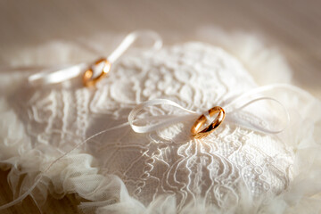 Precious gold wedding rings resting on an elegant white lace cushion - 575039562