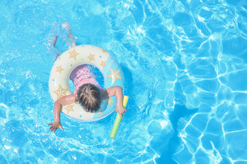 small child swimming with a balloon, view from above.  Summer blue water sunny day