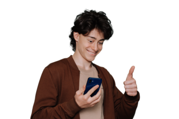 Handsome schoolboy in brown jacket holds phone gestures thumb up during video call by smartphone toothy smiles standing against transparent background. Cheerful guy happy gets great news.