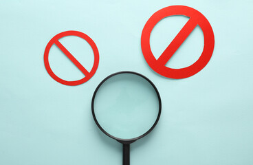 Magnifying glass with prohibition sign on blue background