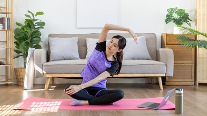 Obraz premium Beautiful healthy woman practicing yoga, Stretch or warm up before exercising, Calming the mind and meditating in her living room, Dumbbells and a protein shake or bottle of water, Healthy exercise.