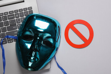 laptop, Anonymous mask with a prohibition sign on gray background. Cyber attack - obrazy, fototapety, plakaty