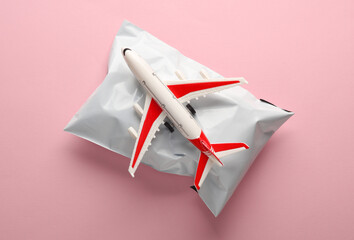 Postal package with air plane on pink background. Cargo transportation, delivery. Top view