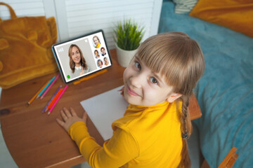 Cheerful young student child girl with gigital tablet at home. Online education and learning concept