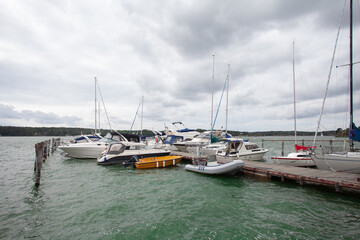 Fototapeta premium Yachts and boats on wooden pier on the background of cloudy sky