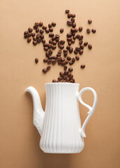 Ceramic teapot with coffee beans on brown background. Top view