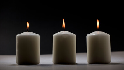 Fototapeta na wymiar three burning candles on white table with black background, space for text