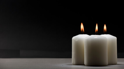 three burning candles on white table with black background, space for text