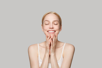 Geogeous blonde woman with ponytail smiling isolated on grey background