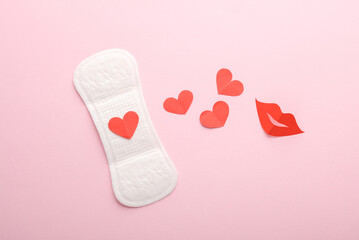 Menstrual pad with hearts and lips on a pink background. Flat lay