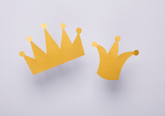Two paper golden crowns on a gray background