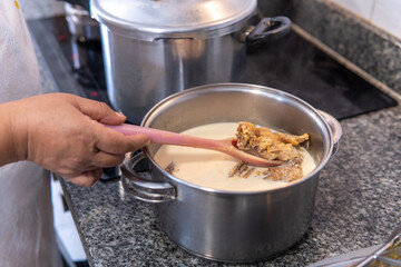 Hand stirring salted cod from the pot by removing the salt with milk