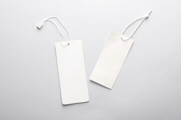 White Blank clothing price tags or labels mockup with strings on gray background. Sale, shopping concept. Top view