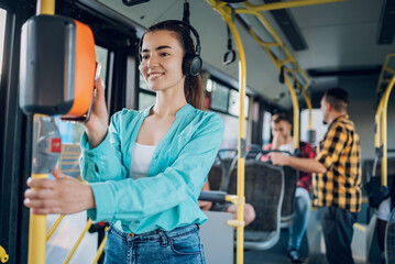 Woman riding in a bus and using a smartphone for paying a ticket