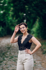 Stylish woman wearing beige pants and a black lace top walking in the nature