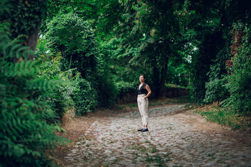 Fototapeta na wymiar Stylish woman wearing beige pants and a black lace top walking in the nature