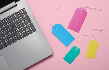 Price tags with laptop on pink background. Online shopping. Top view