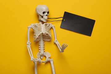 Halloween sale, black friday. Skeleton with price tag on yellow background