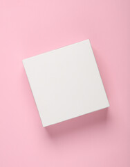 Fototapeta na wymiar White empty box on a pink background. Top view