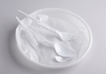 Broken plastic plate, fork and spoon on a gray background. Stop plastic pollution, recycling, eco concept